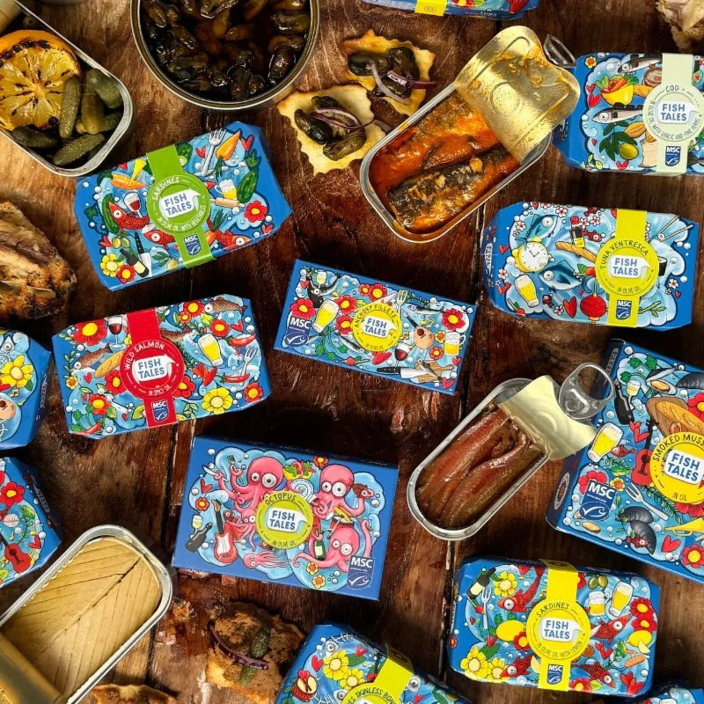 Bovenaanzicht van blikjes vis, olijven, augurken en crackers op een houten tafel
