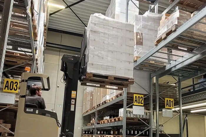 Magazijn met heftruck, pallets en stellingen vol flessen