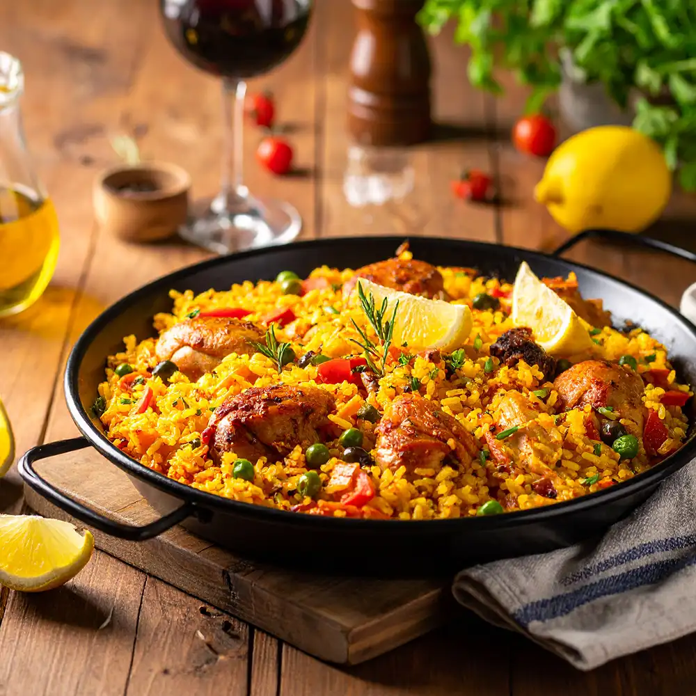 Paella met kip, paprika en doperwten in een paellapan